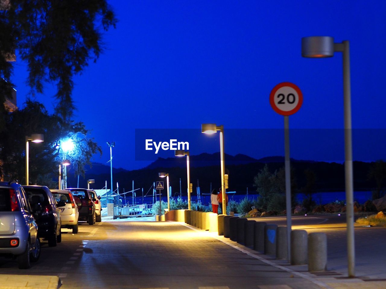 Cars parked on illuminated street against sky at dusk