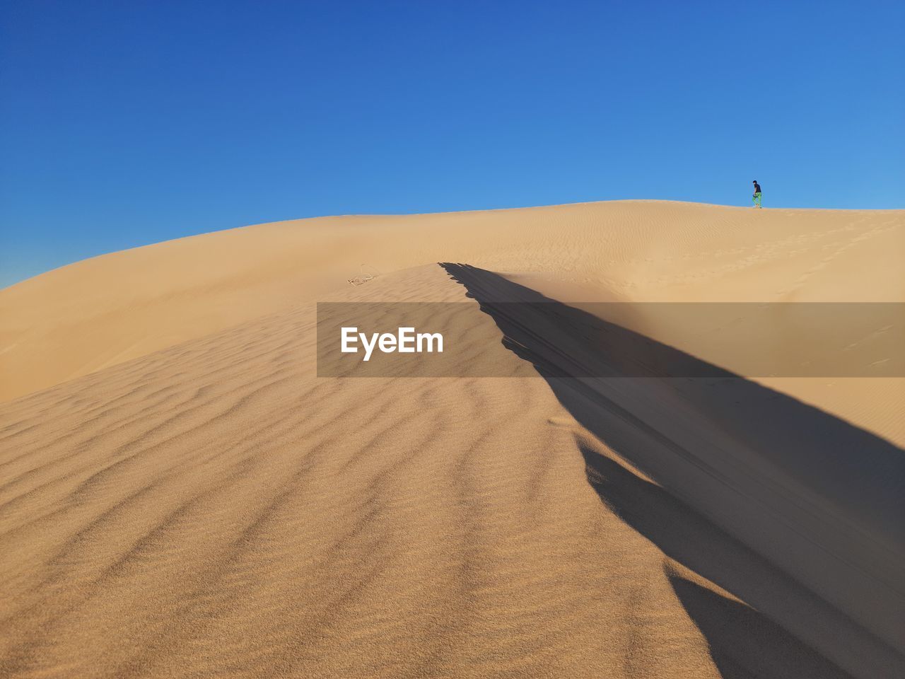 Sand dunes in desert against clear blue sky