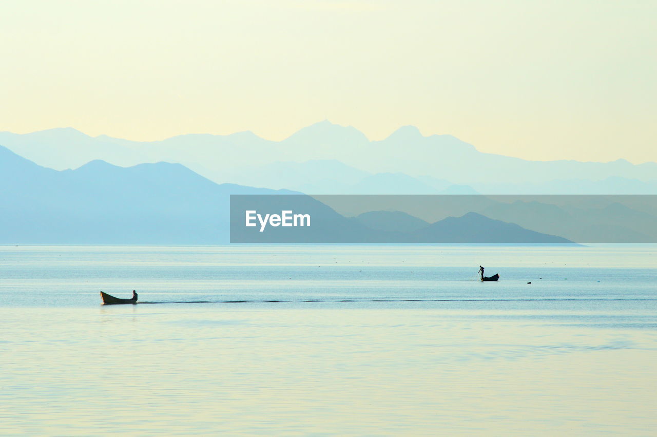 Silhouette boats in sea against sky