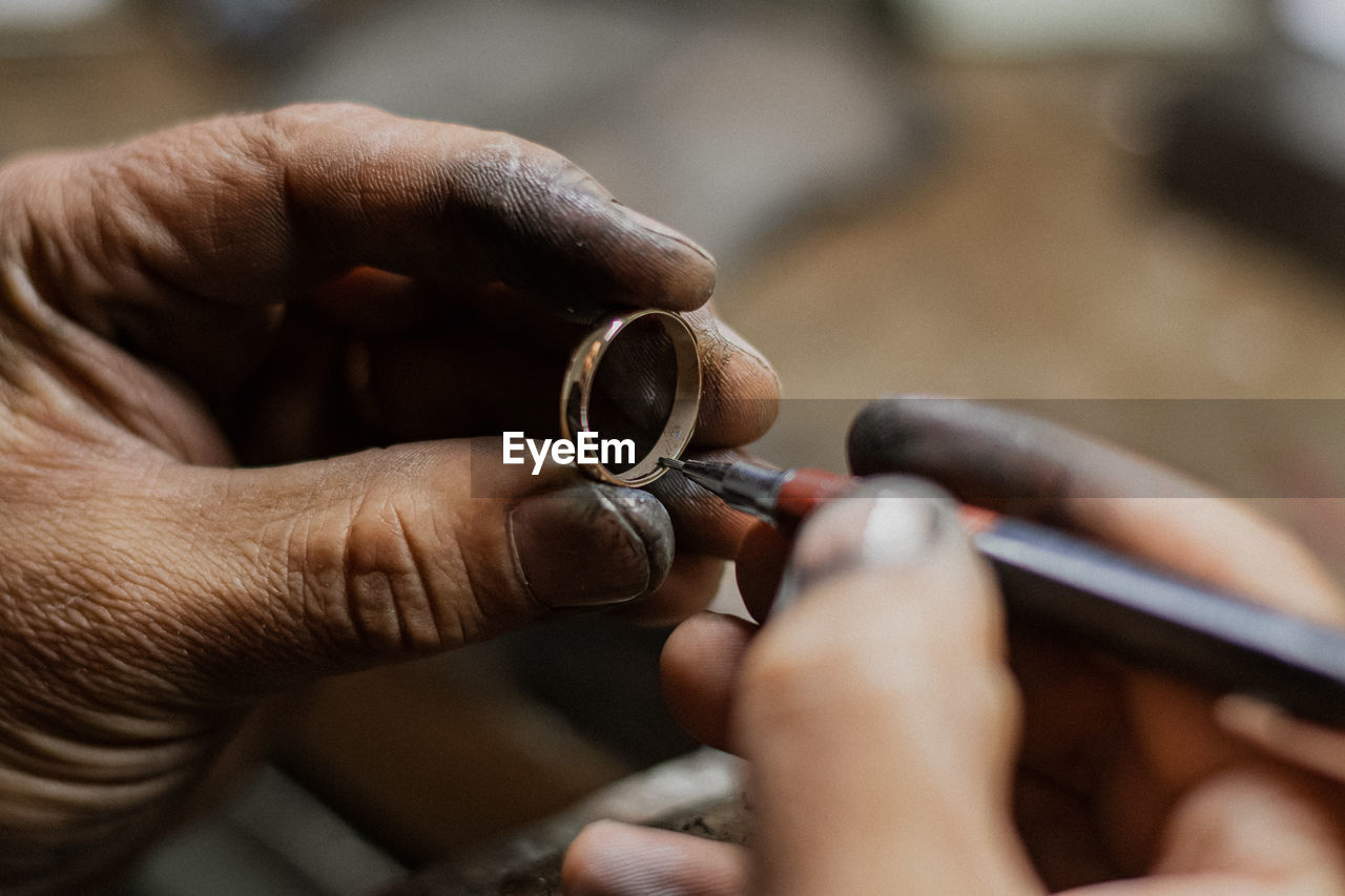 Cropped hands holding pen and ring