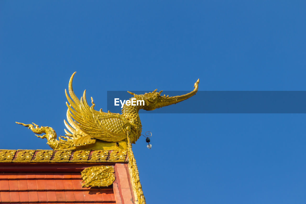 LOW ANGLE VIEW OF STATUE AGAINST BUILDING AGAINST BLUE SKY