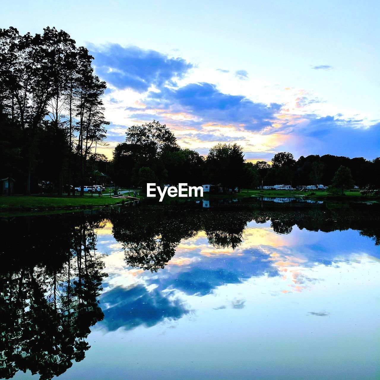 REFLECTION OF TREES ON LAKE AGAINST SKY