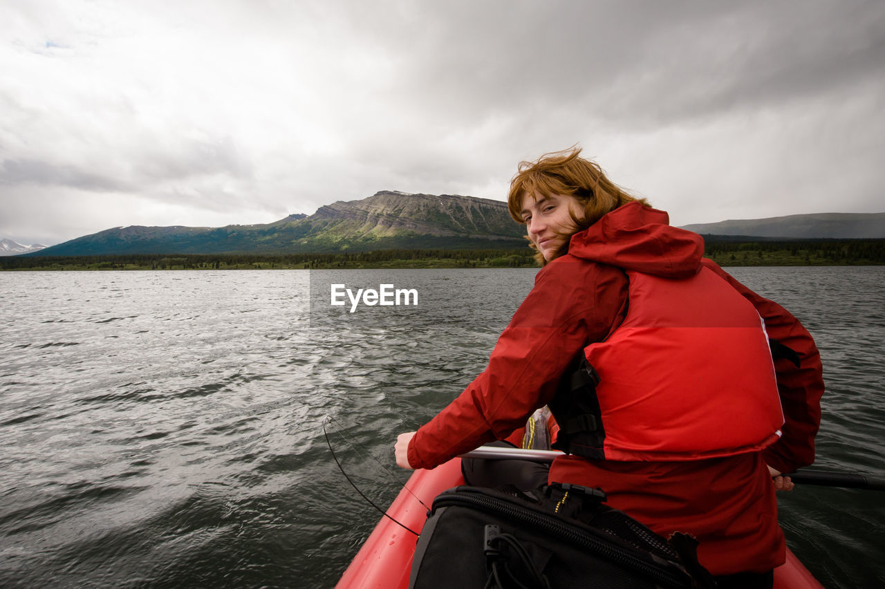 Portrait of man sitting on boat in river against sky