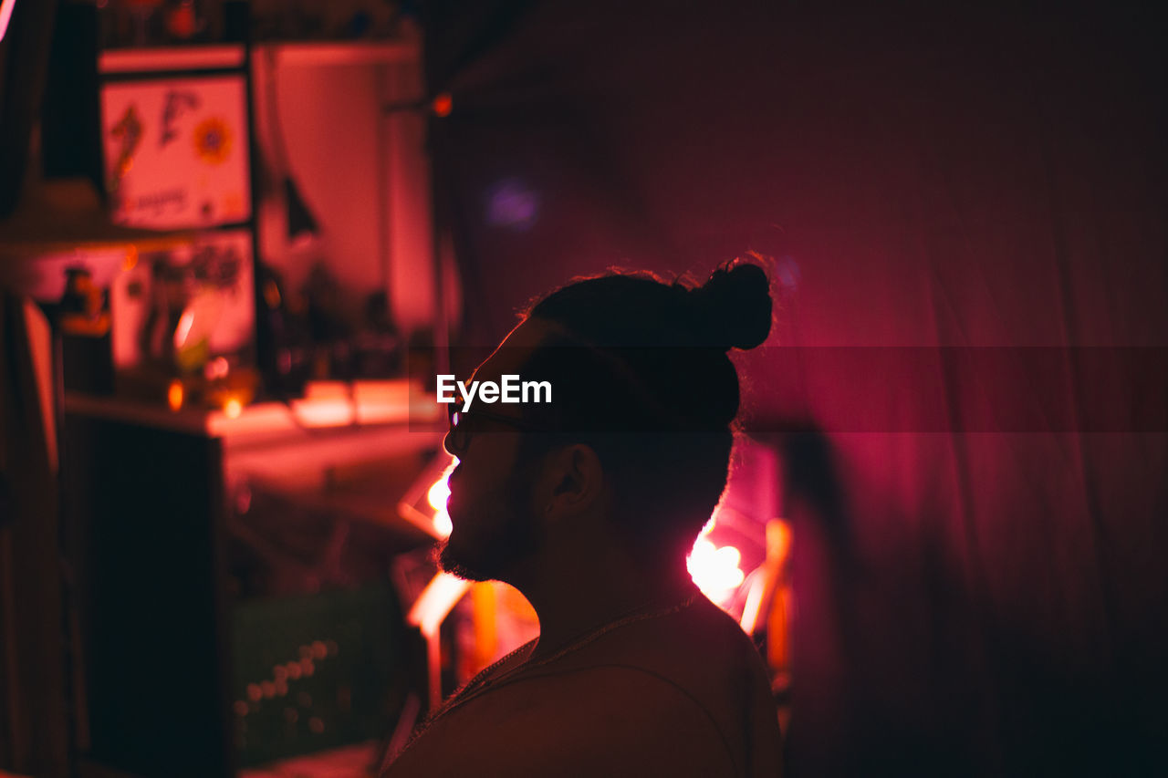 Side view of man sitting in illuminated room