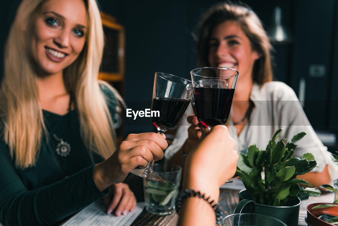 Cheerful female friends toasting wineglass at table in restaurant