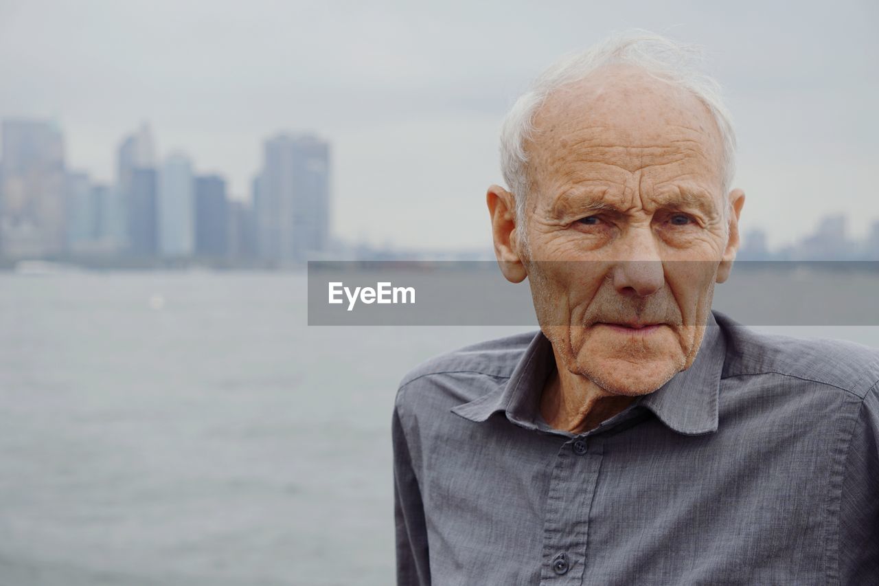 Portrait of senior man in city against sea