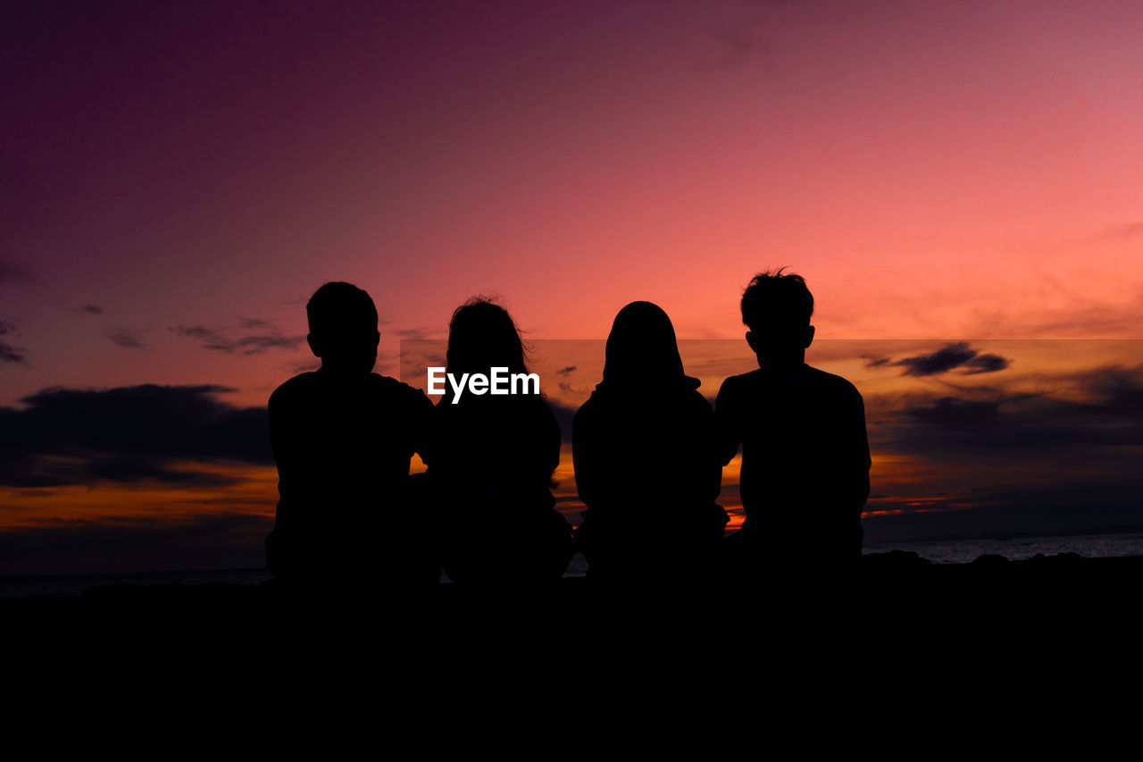 Silhouette people looking at sea against sky during sunset