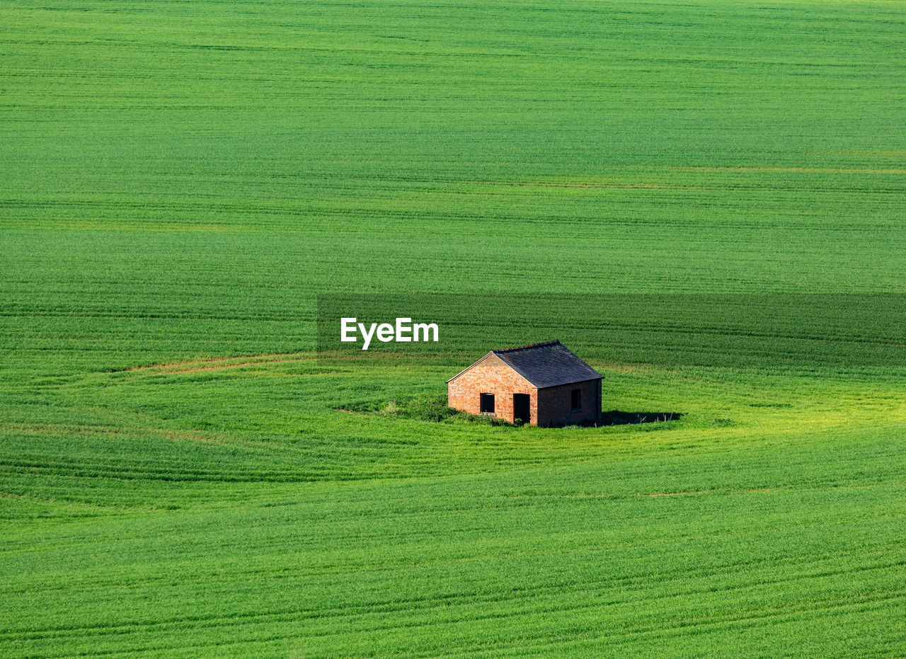 House on green field against sky