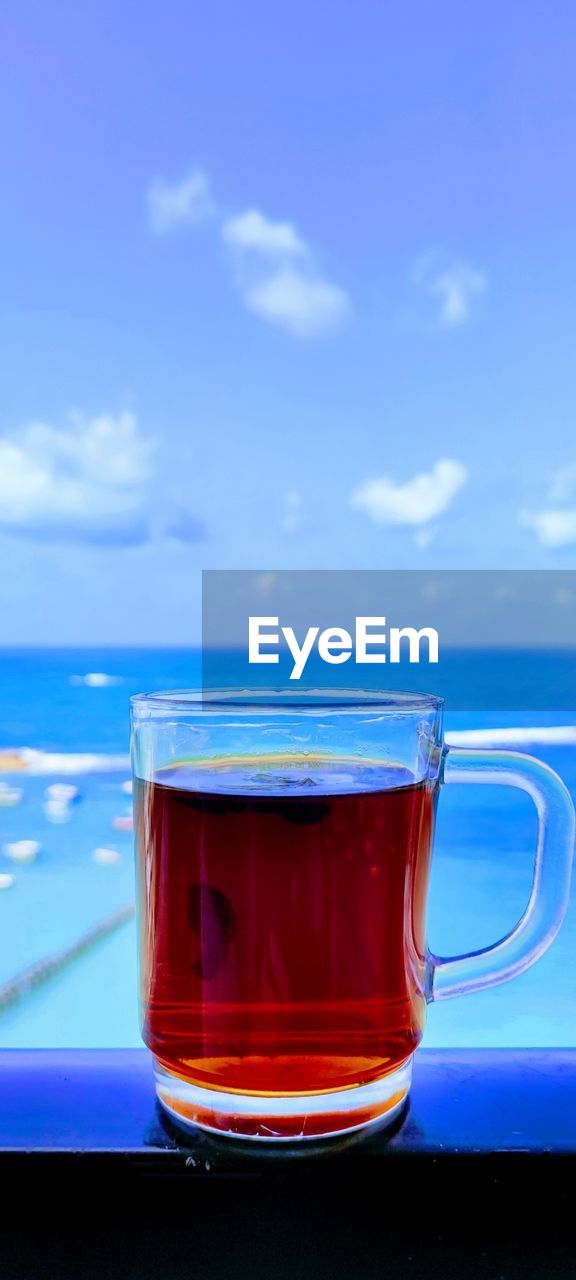 Close-up of tea in glass on table against blue sky