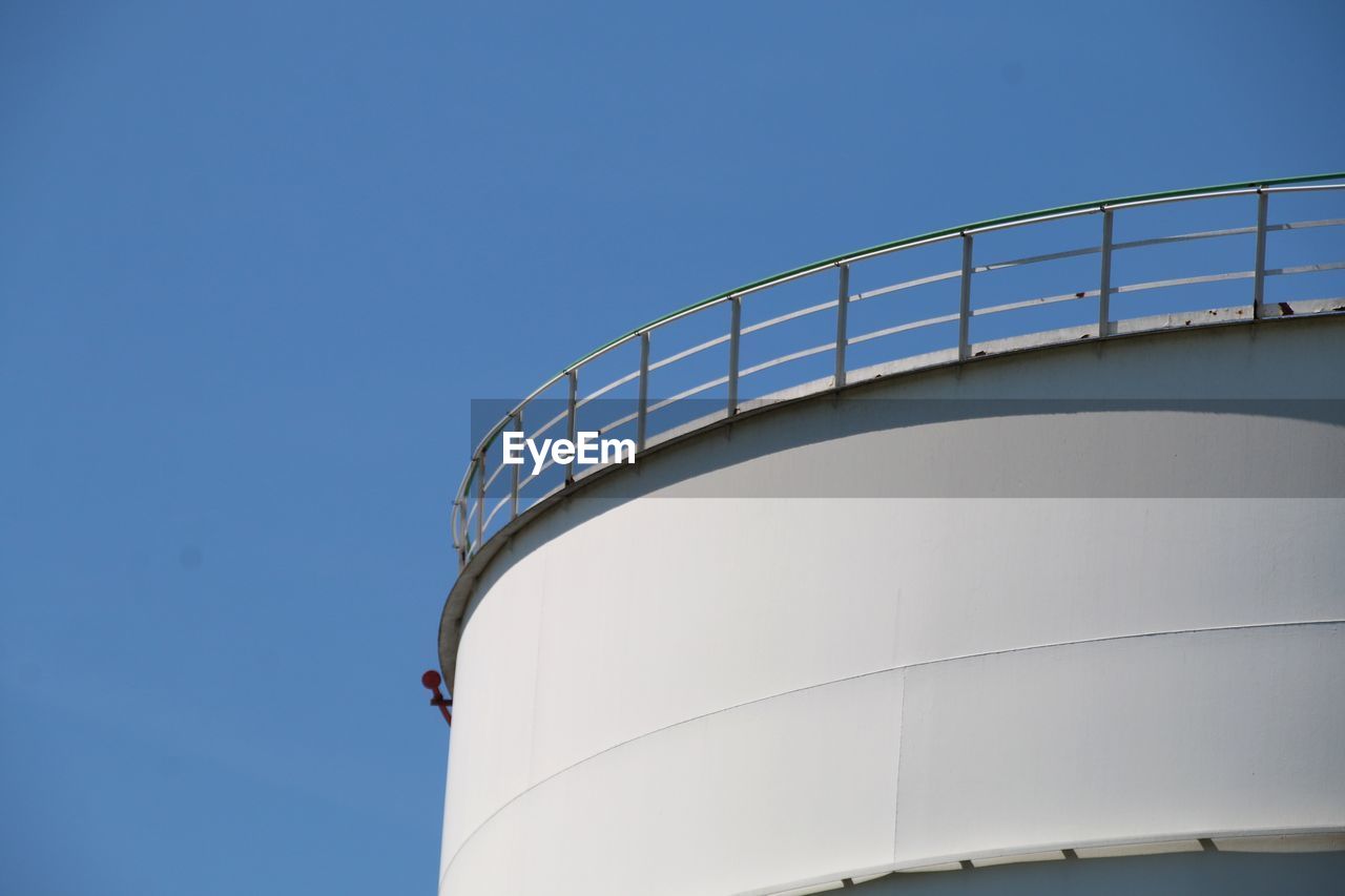 Low angle view of railing against clear blue sky