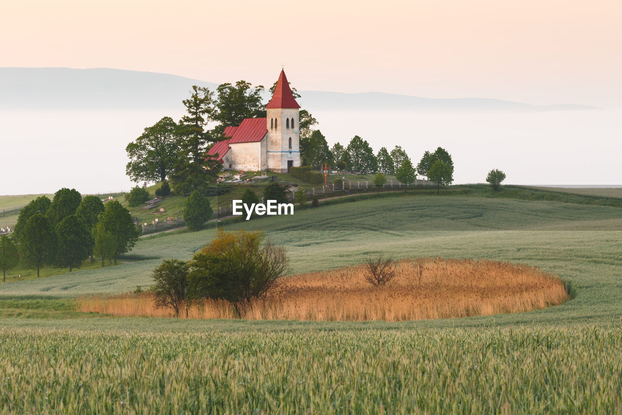 Rural gothic church in a cemetery on a foggy morning.