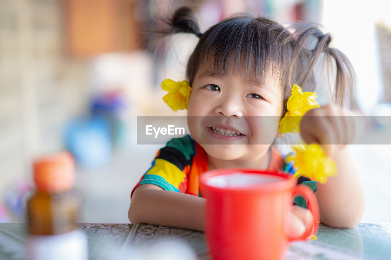 Portrait of cute girl drinking glasses on table