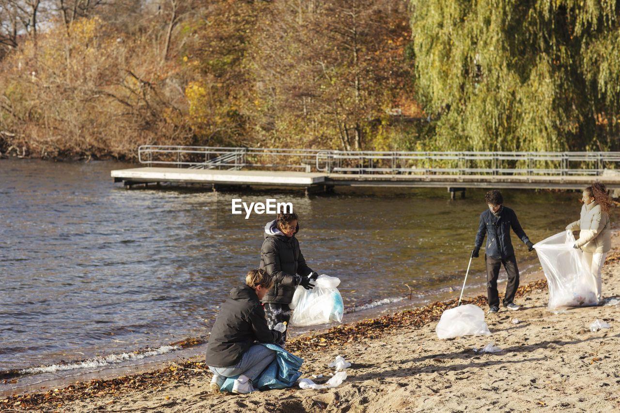 Male and female friends collecting plastic garbage by lake