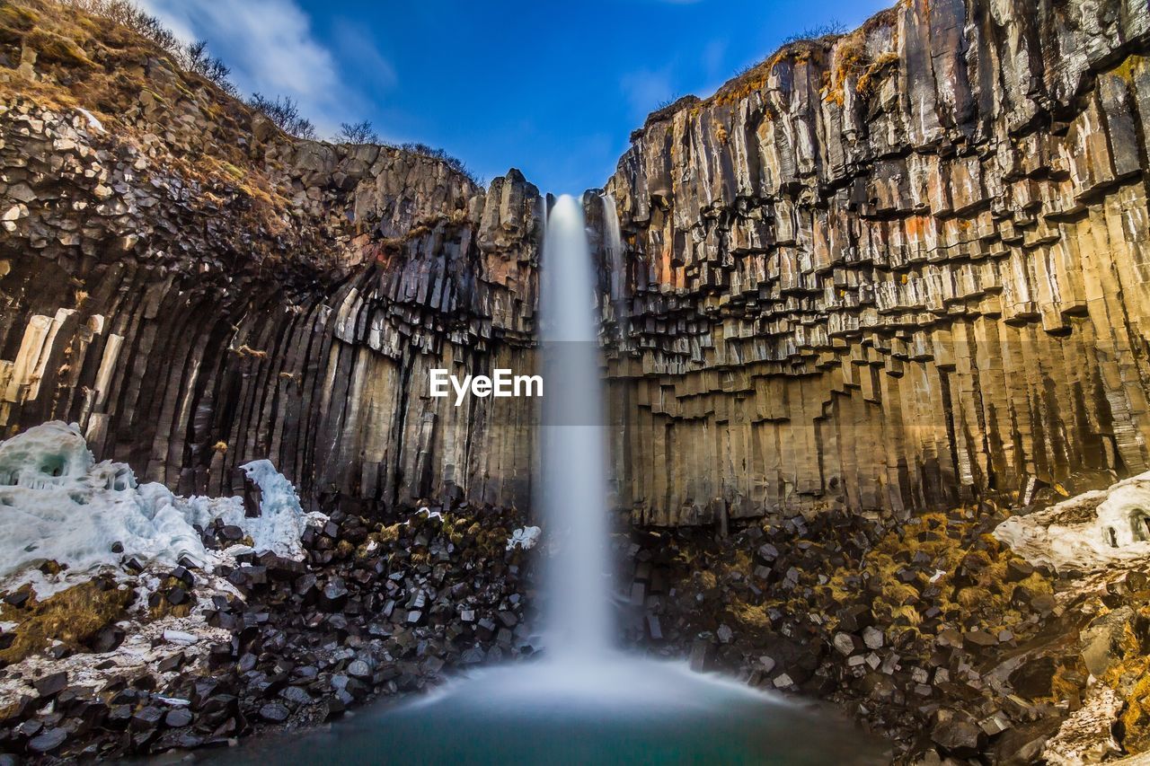 Scenic view of waterfall falling from mountain