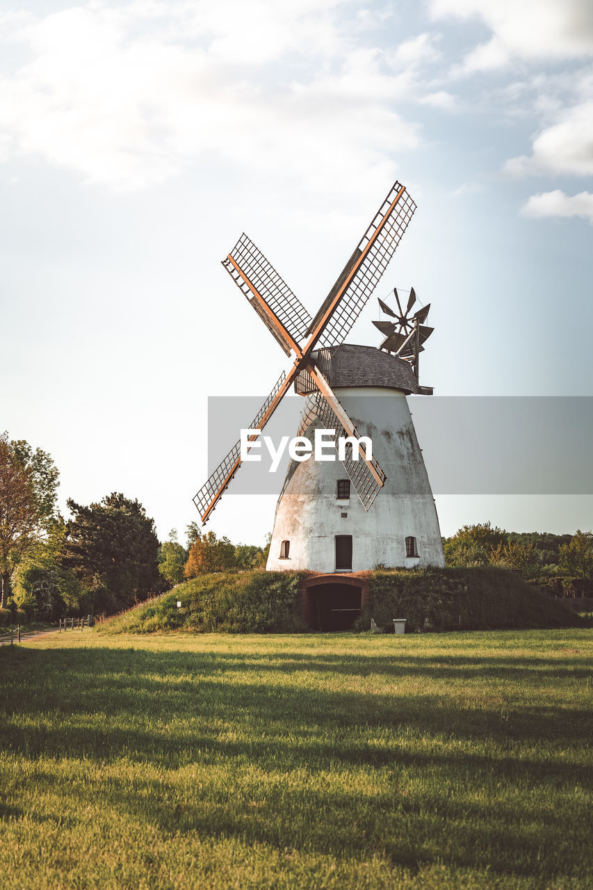 Traditional windmill on field against sky