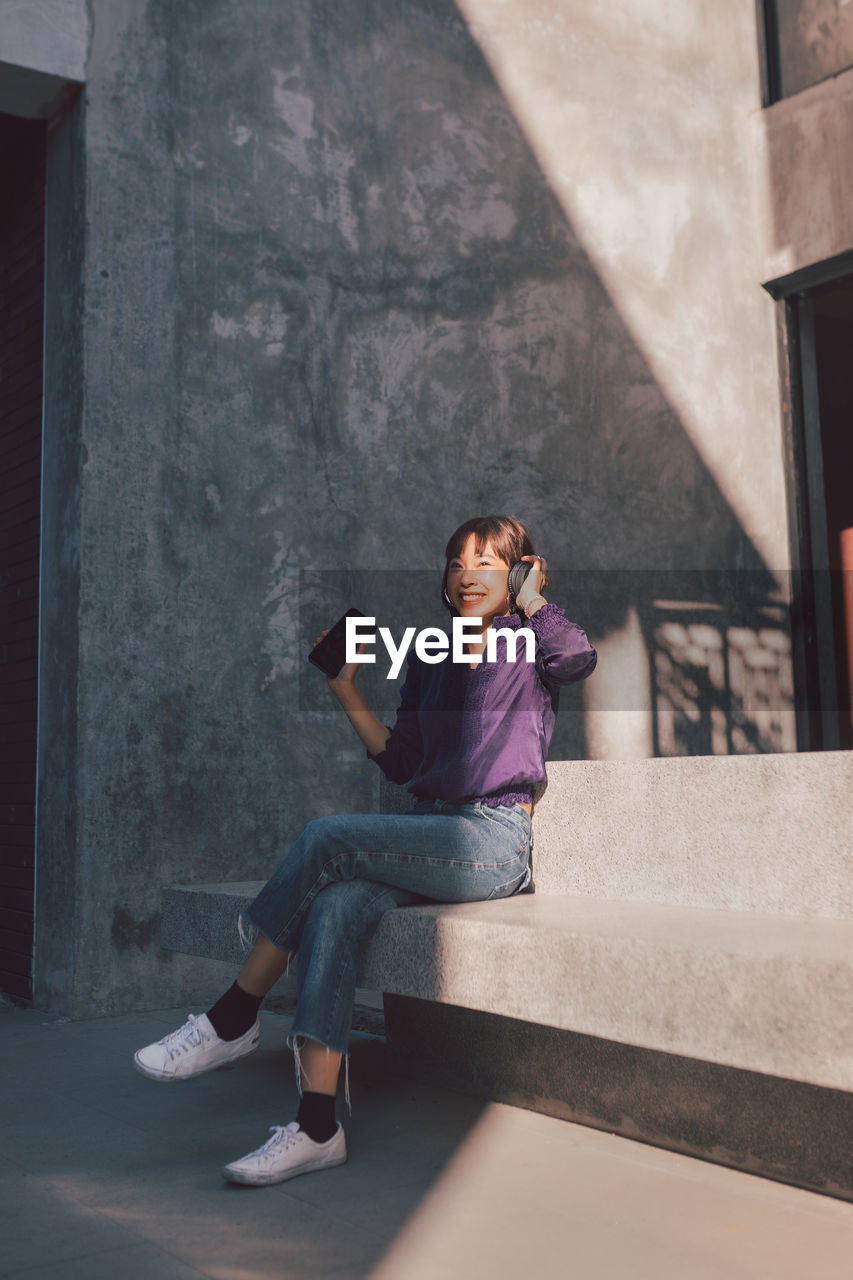 PORTRAIT OF WOMAN SITTING ON WALL