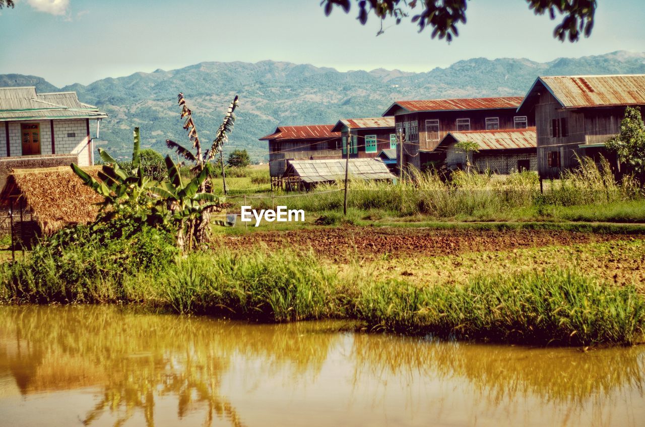 Houses by lake against sky