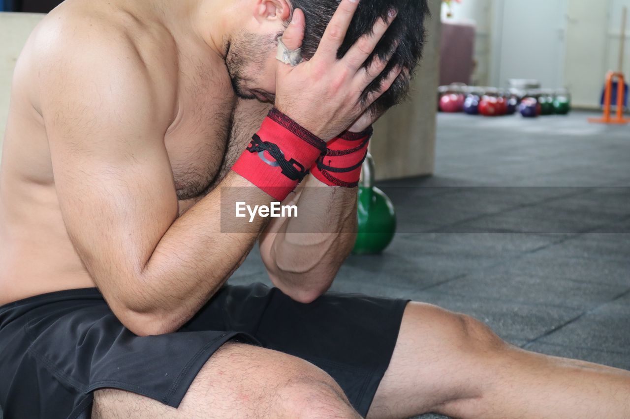 Tired muscular man relaxing in gym