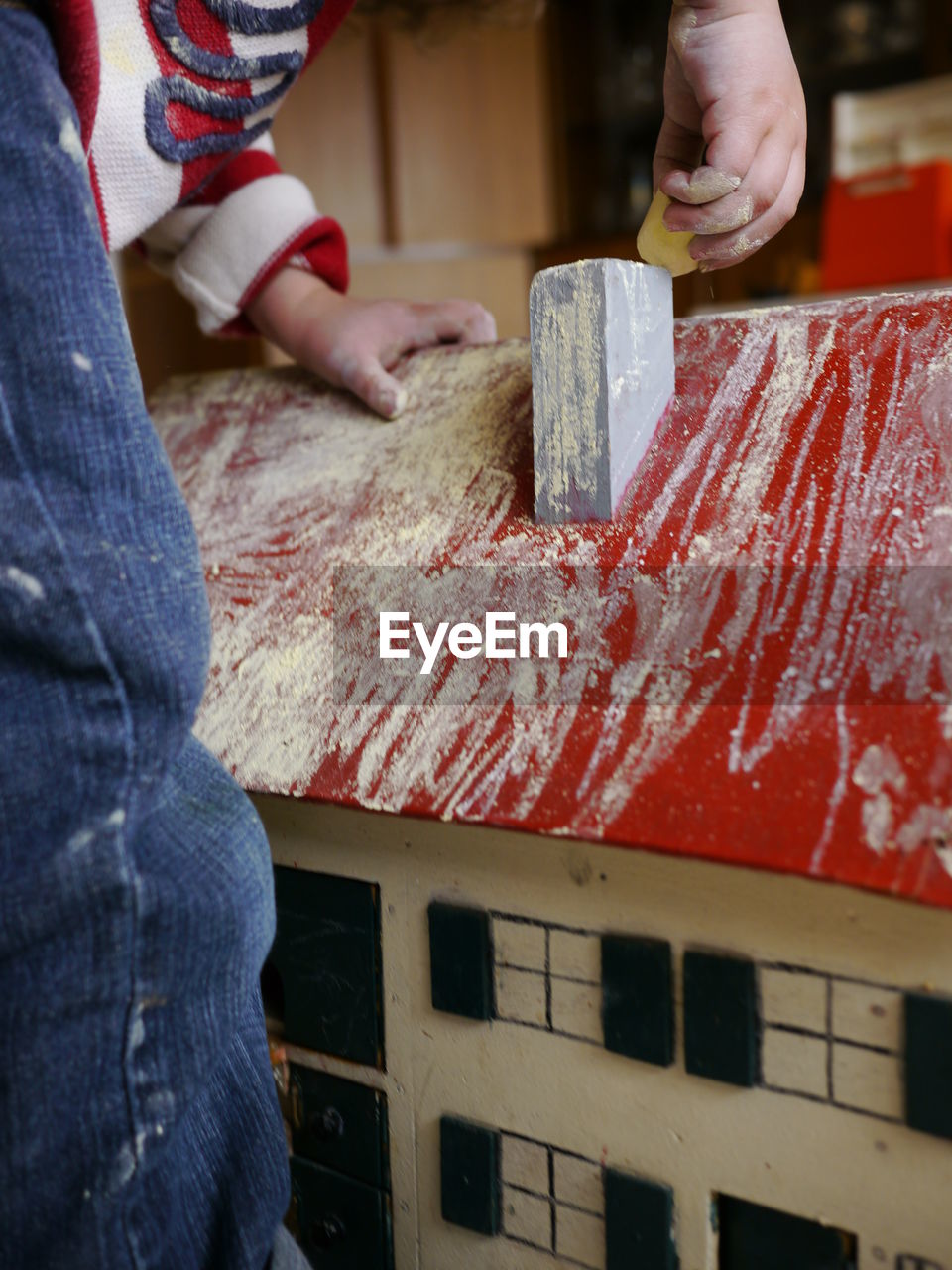 Midsection of boy coloring model house with chalk