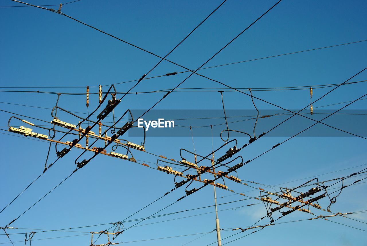 Low angle view of electricity pylon against blue sky