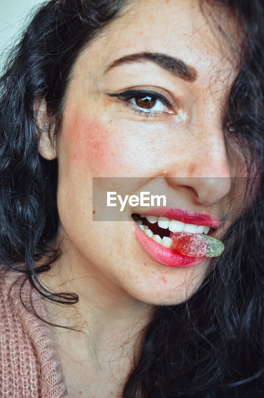 Close-up portrait of smiling woman eating candy