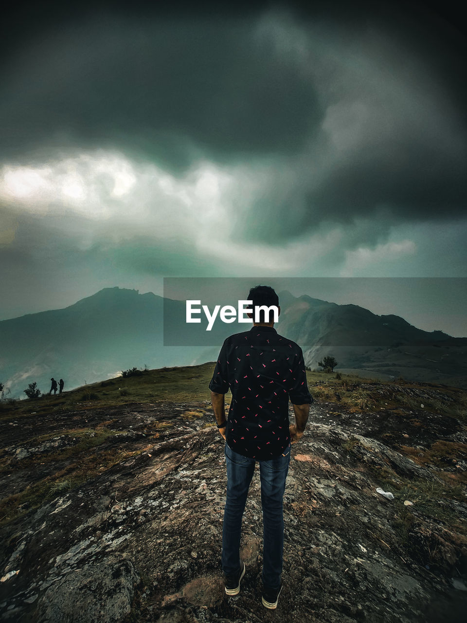 Rear view of man standing on mountain against sky