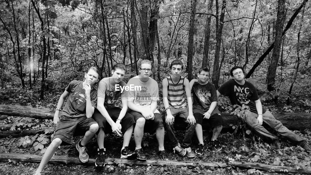 FRIENDS STANDING ON TREE TRUNK