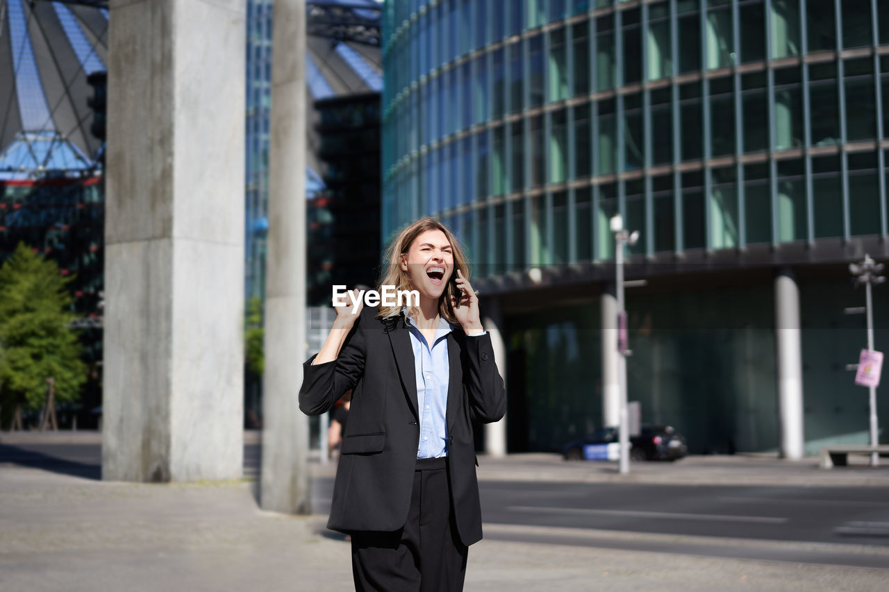 portrait of young businesswoman standing against building