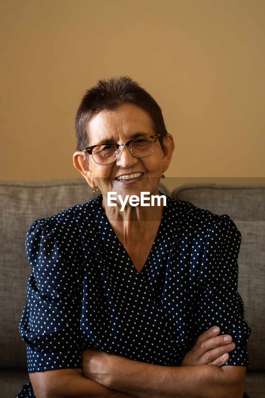Portrait of smiling senior woman in eyeglasses sitting at home