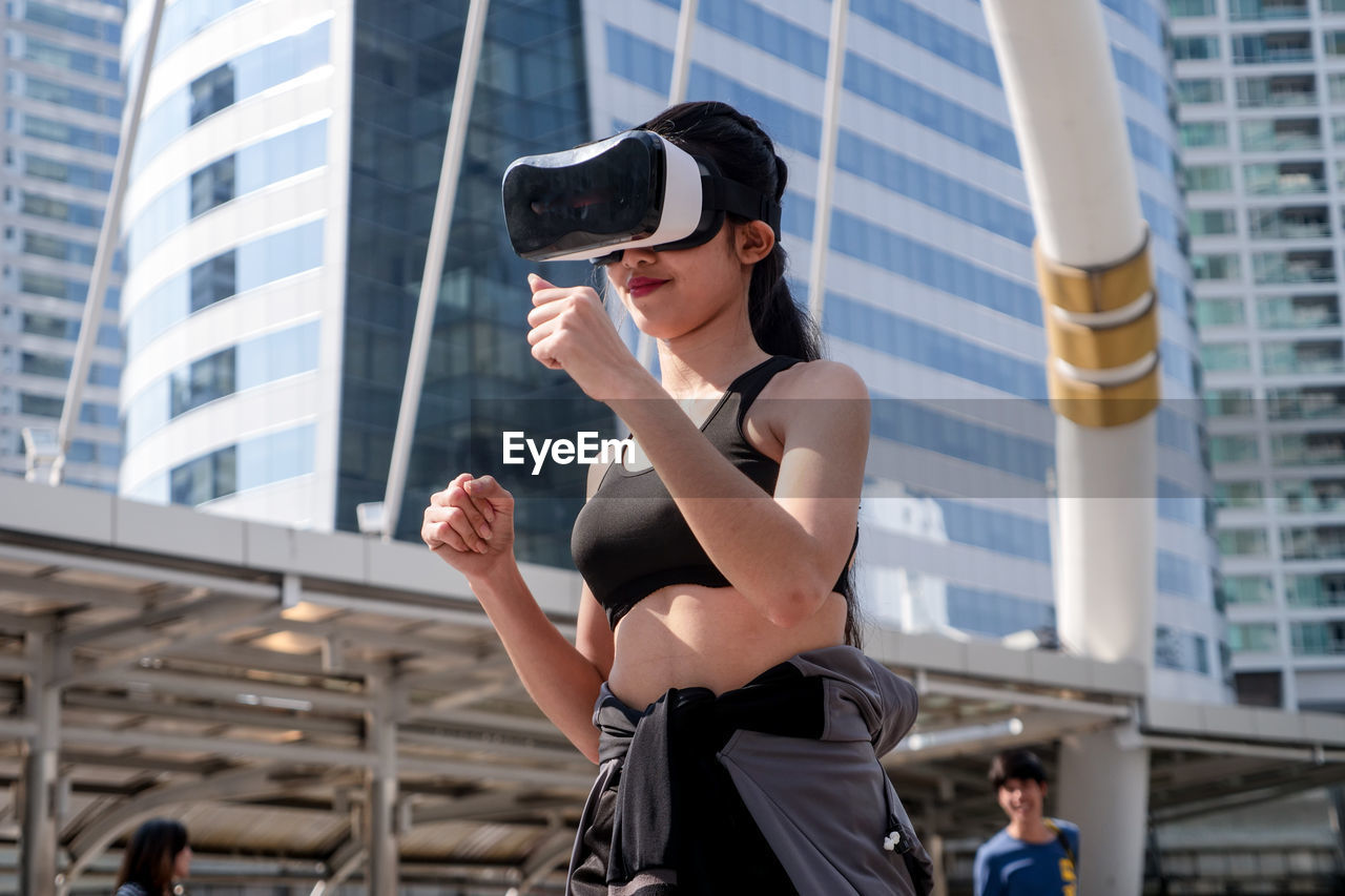 Low angle view of woman using virtual reality simulator in city
