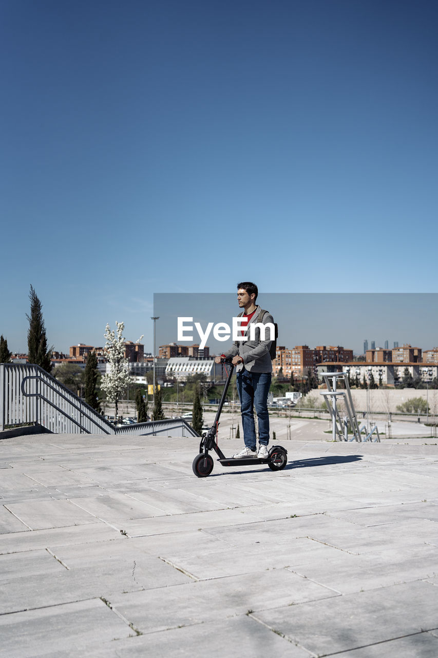 Man riding electric scooter on footpath