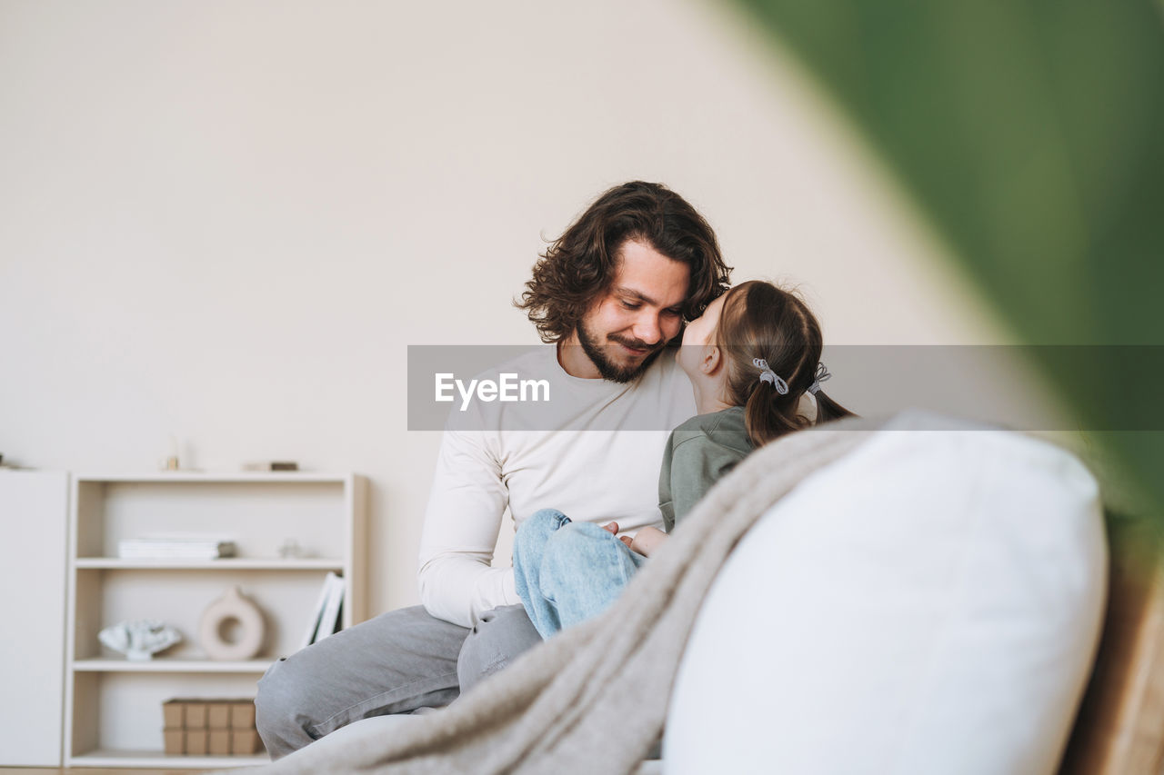 Young happy family with father and daughter on sofa in the cozy home, father day