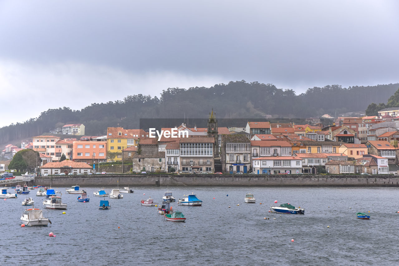 Coastal village in the background and fishing boats in the sea in the foreground. galicia, spain
