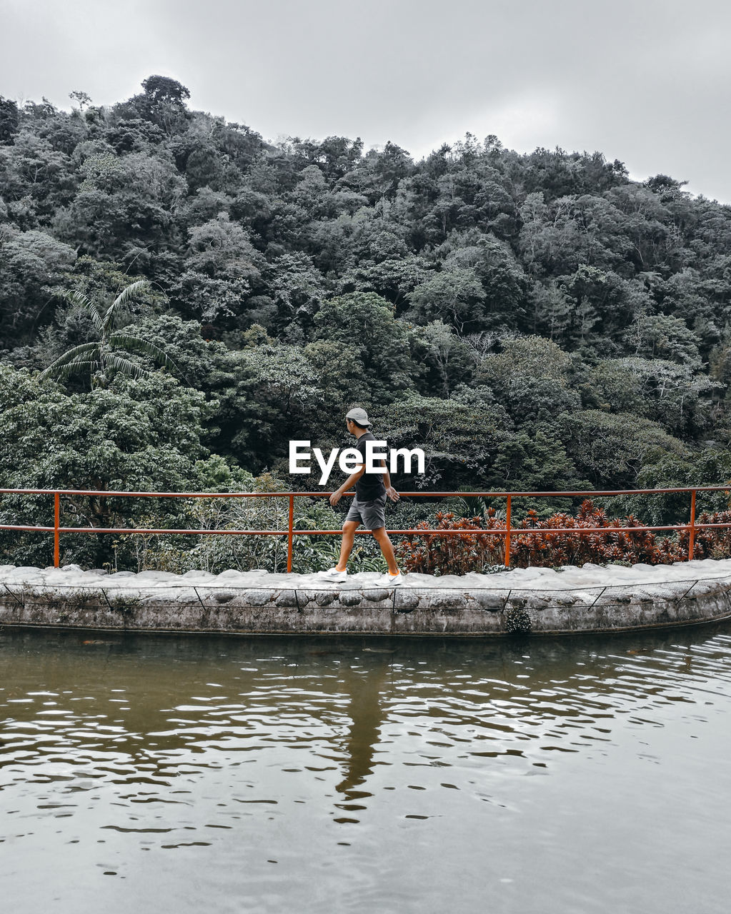 MAN STANDING IN RIVER AGAINST SKY