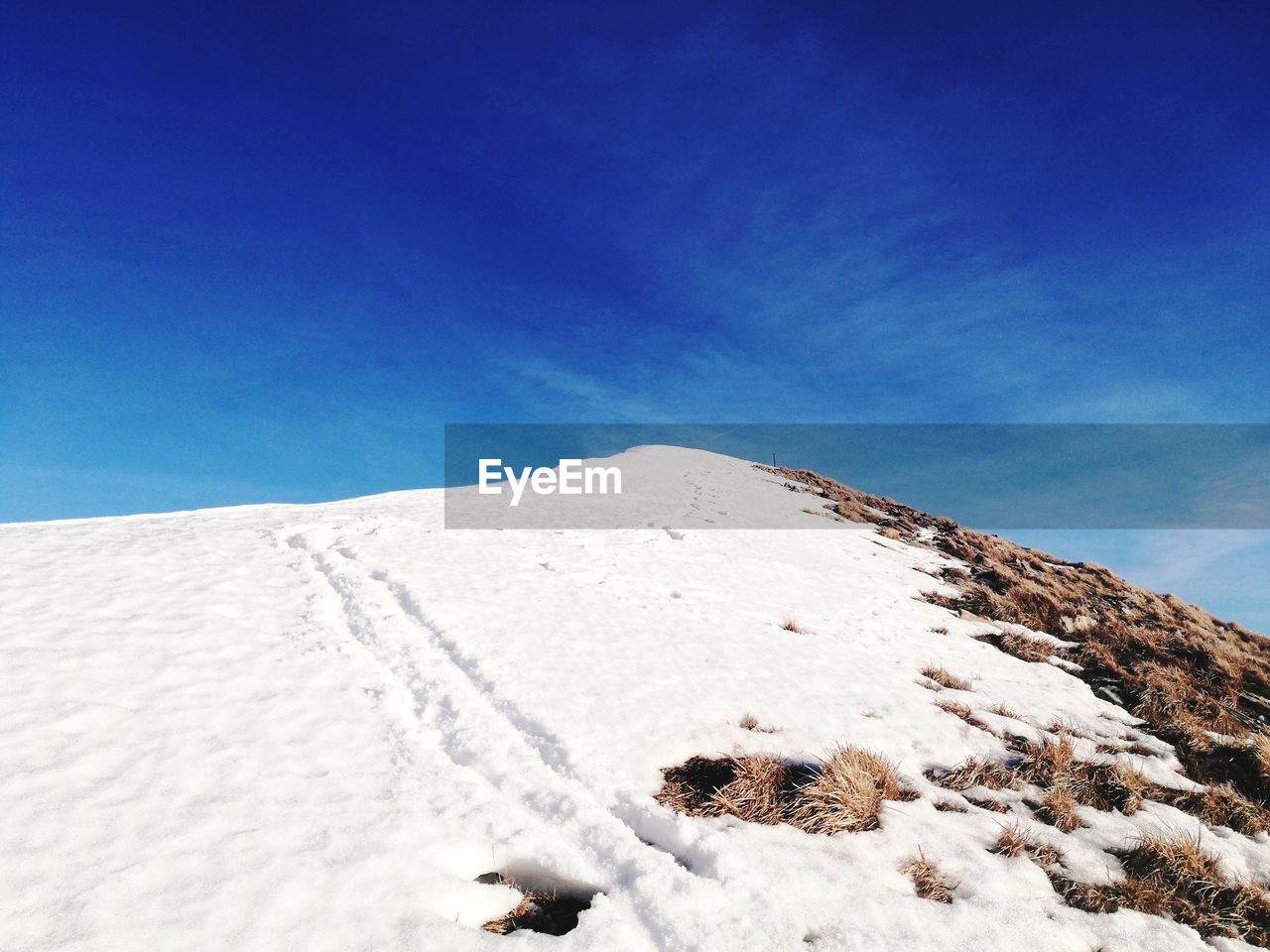 Low angle view of snow covered landscape against blue sky