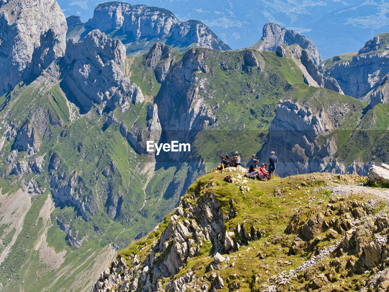 Rear view of group of hikers enjoying the scenic view by alpine landscape