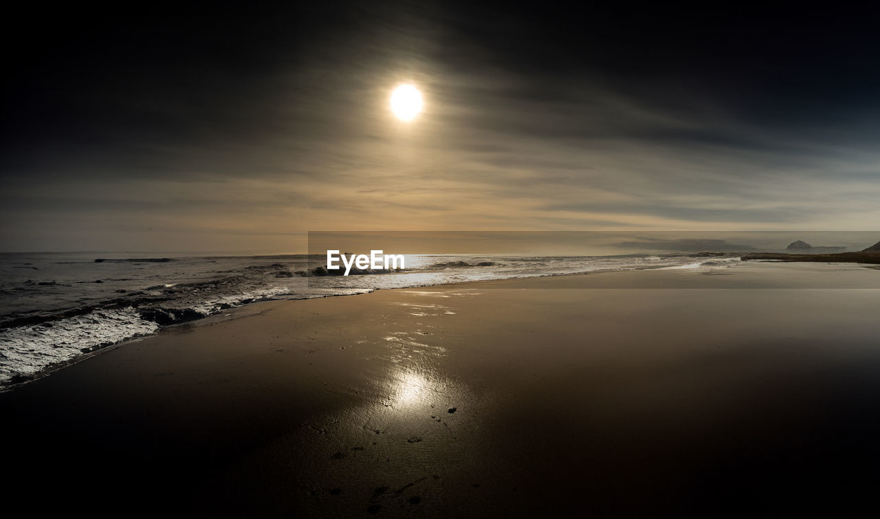 water, sea, sky, light, scenics - nature, land, beach, beauty in nature, sunlight, moon, nature, tranquility, horizon, reflection, tranquil scene, moonlight, cloud, sun, wave, horizon over water, darkness, astronomical object, dawn, ocean, no people, environment, sunrise, sand, outdoors, morning, idyllic, dramatic sky, motion, travel destinations, landscape, full moon, seascape, coastline, wind wave