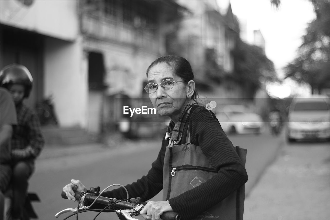 A grandmother is pushing a bicycle to cross the road