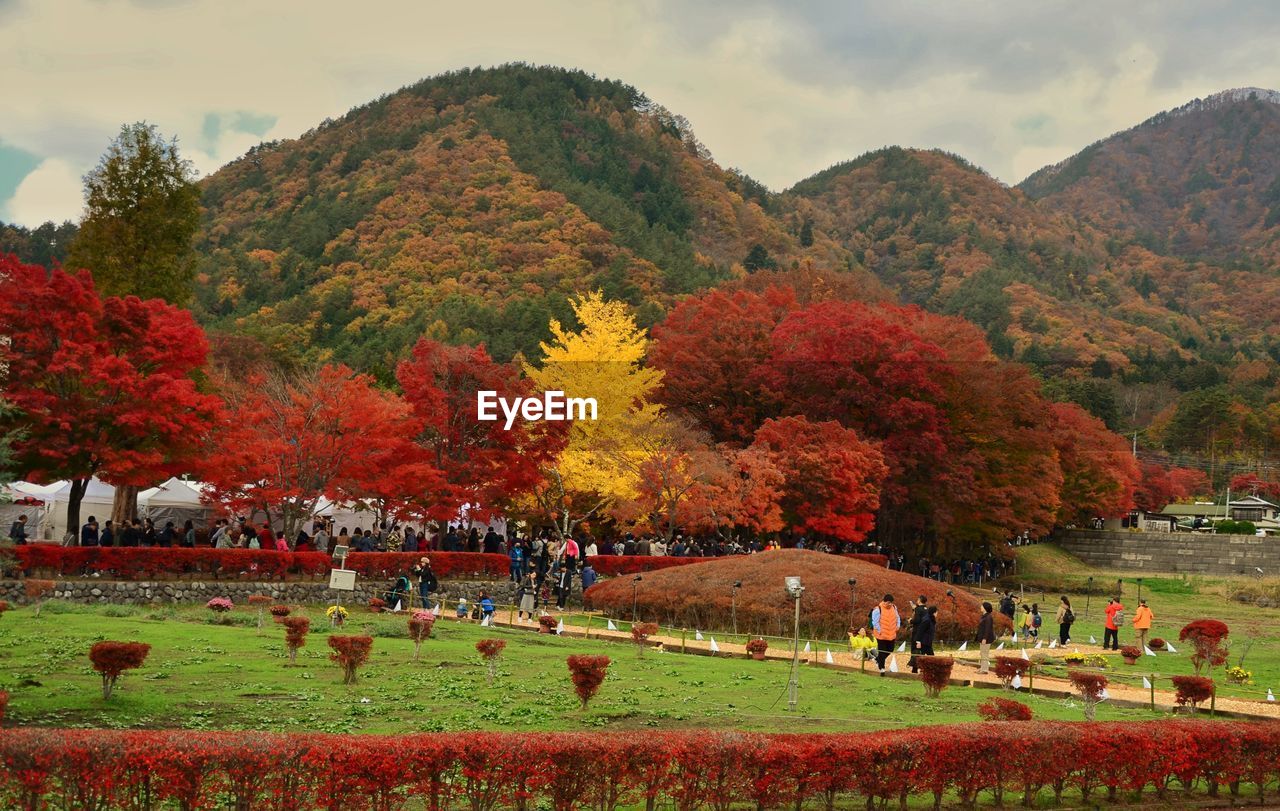 People in park against mountains and sky during autumn