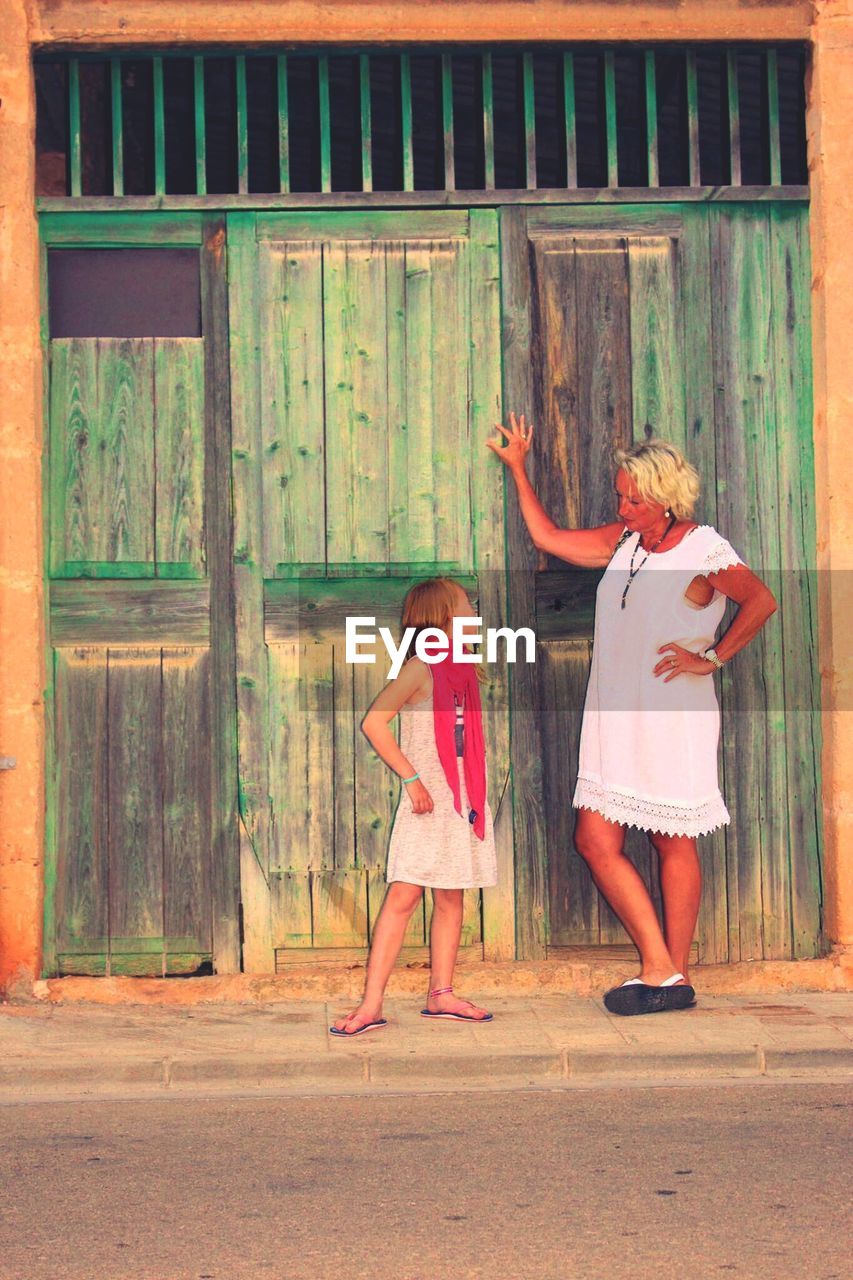 Girl looking at grandmother while standing on footpath