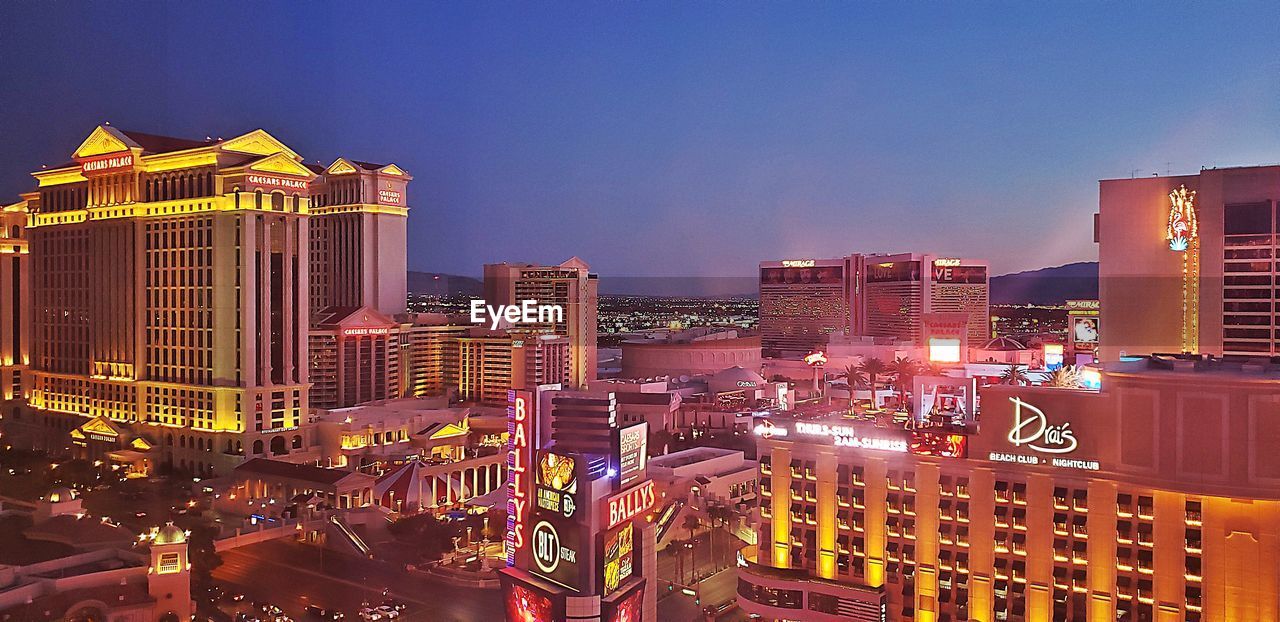 ILLUMINATED BUILDINGS AGAINST CLEAR SKY AT NIGHT