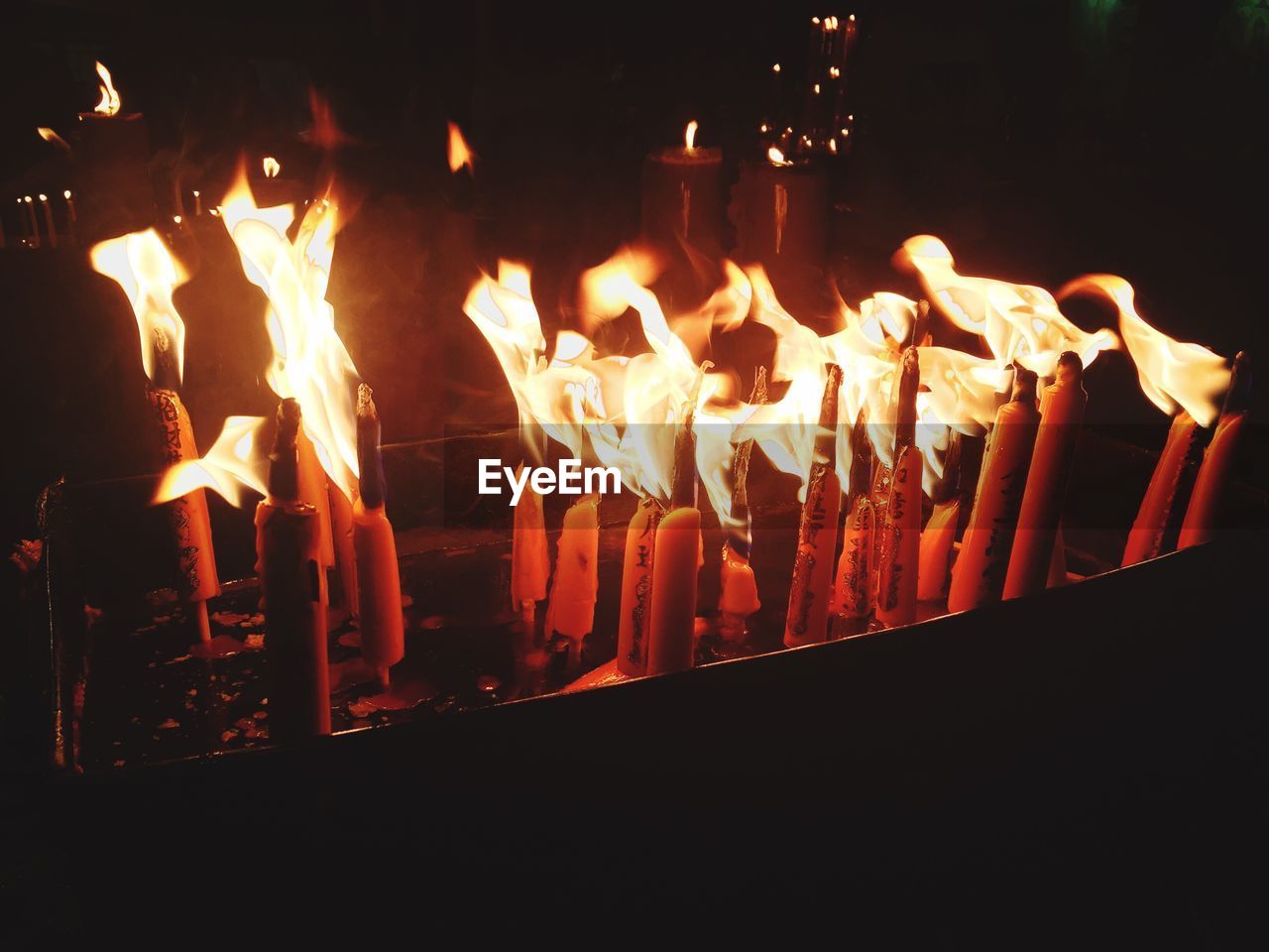 CLOSE-UP OF LIT CANDLES IN DARK