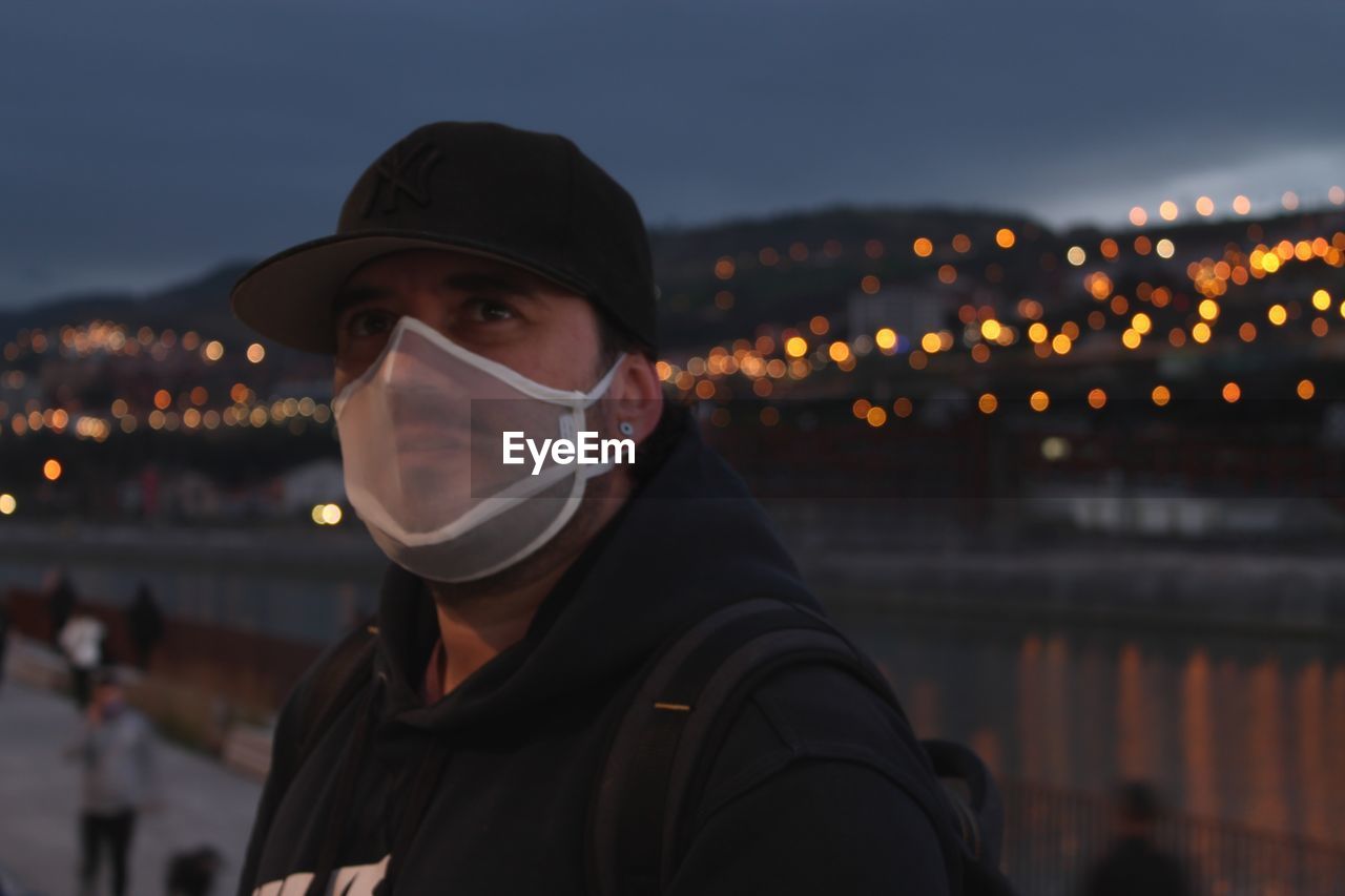 Young man wearing mask looking away at night