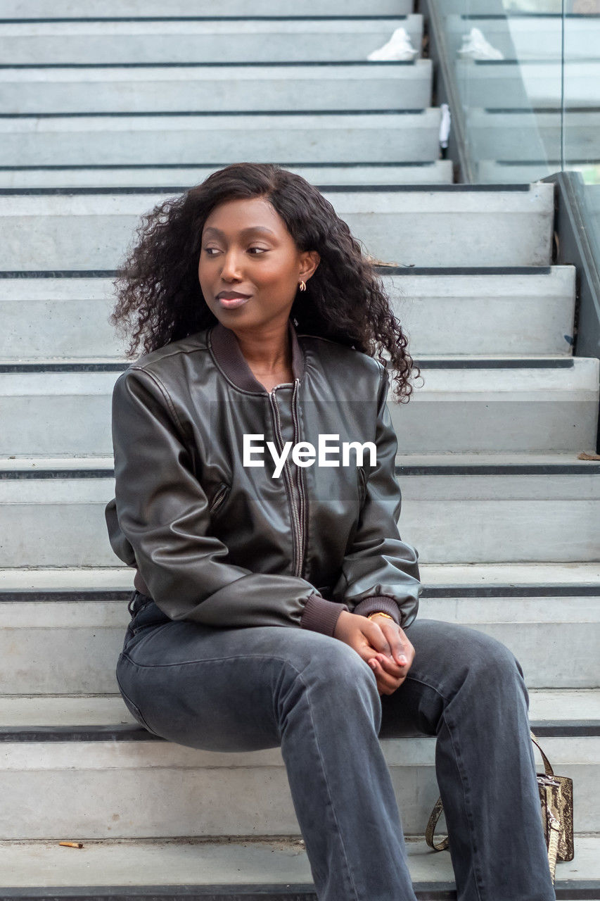 thoughtful young woman sitting against steps