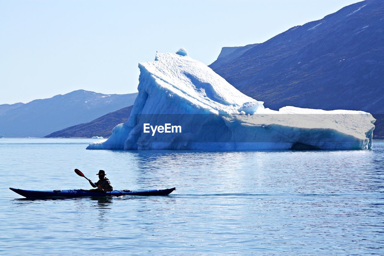 Man kayaking on sea against mountain