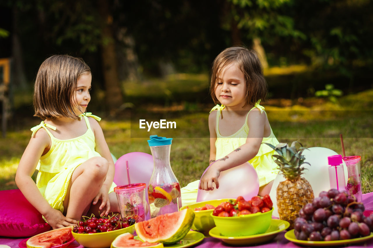 Siblings having food and drink in park