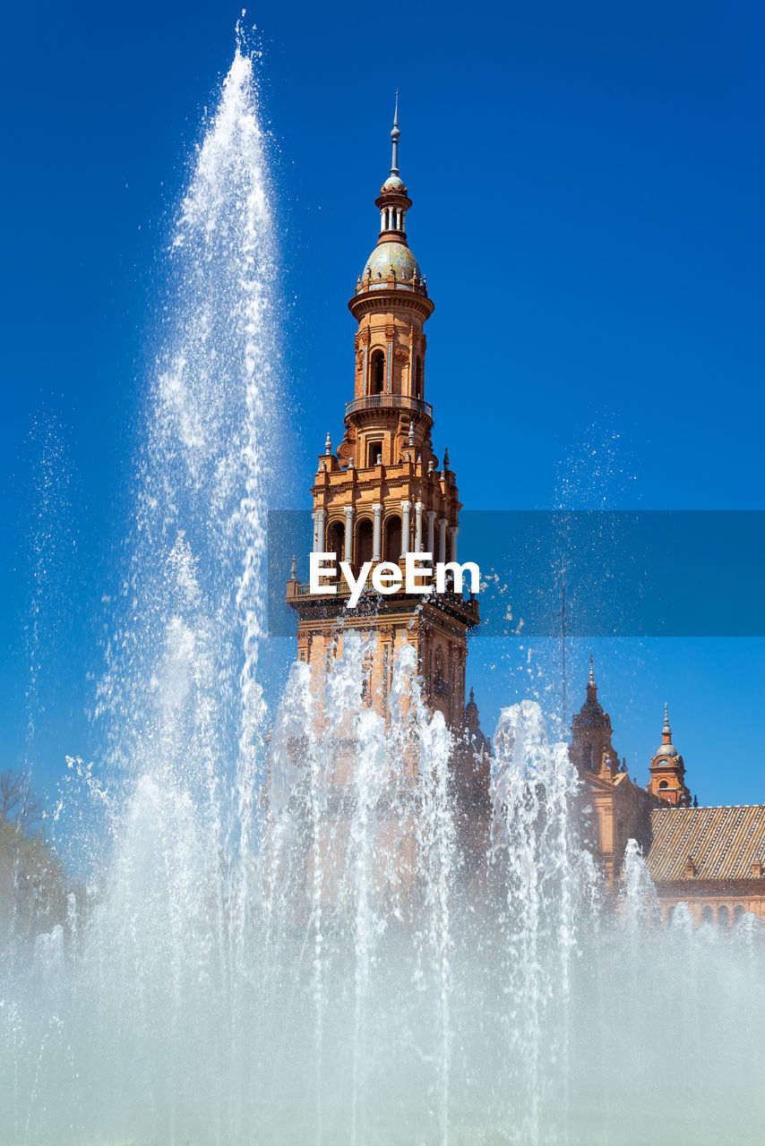 LOW ANGLE VIEW OF WATER FOUNTAIN AGAINST BUILDING