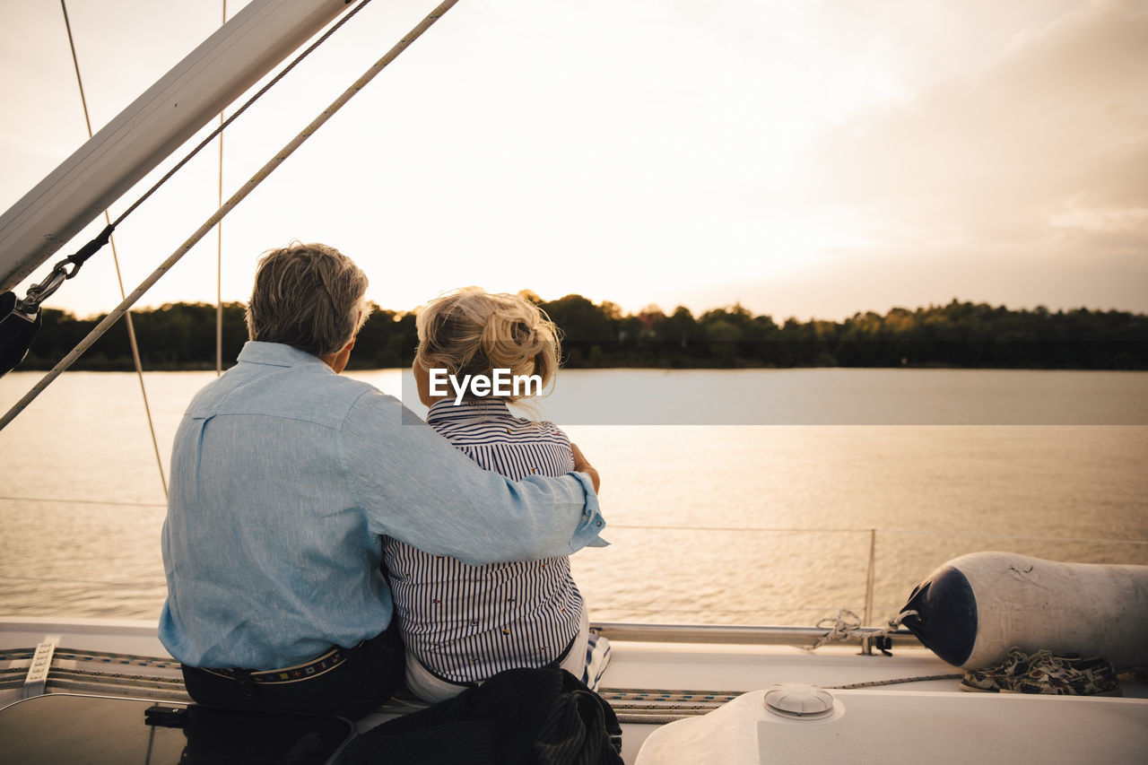 Rear view of senior couple admiring sea during sunset