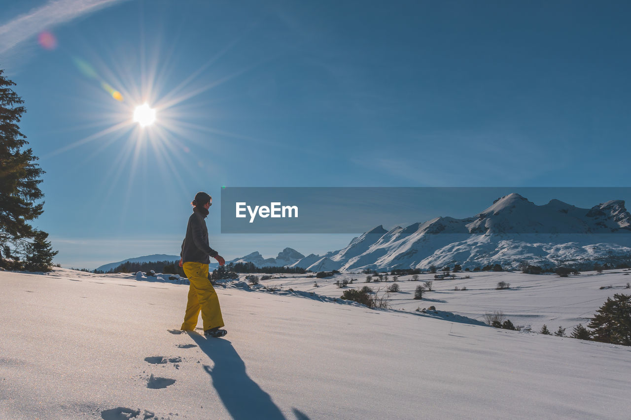 A full-body shot of a young caucasian woman walking towards the camera in the french alps mountains