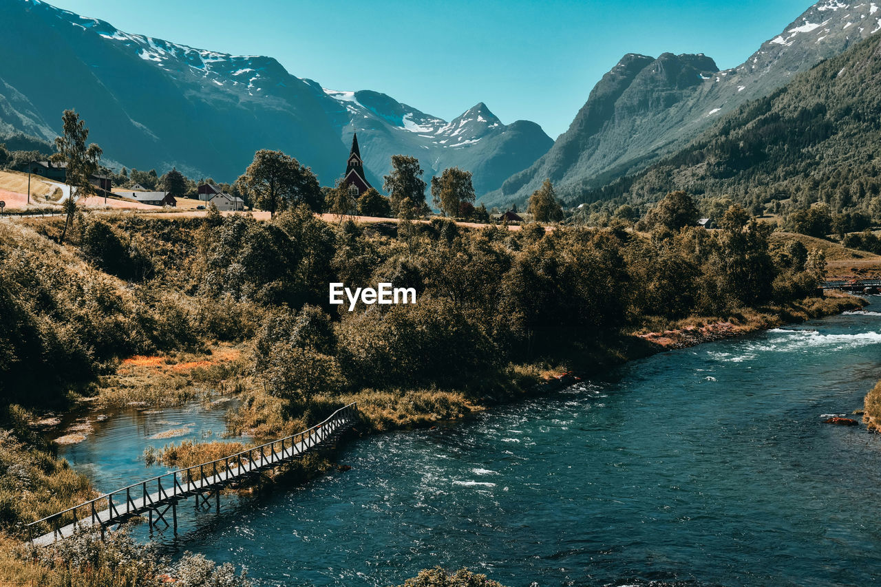 Scenic view of river by mountains against sky